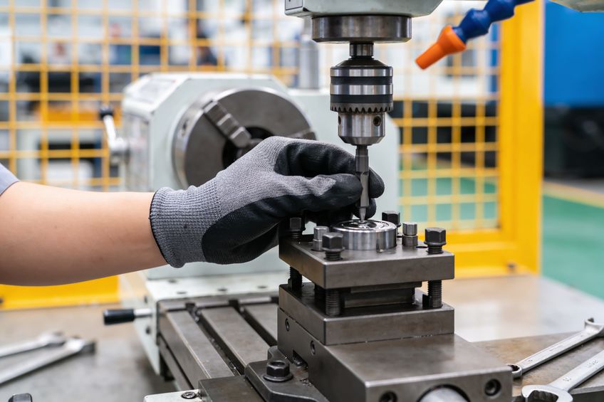 Worker's hand trying to fix industrial machine from vibrating
